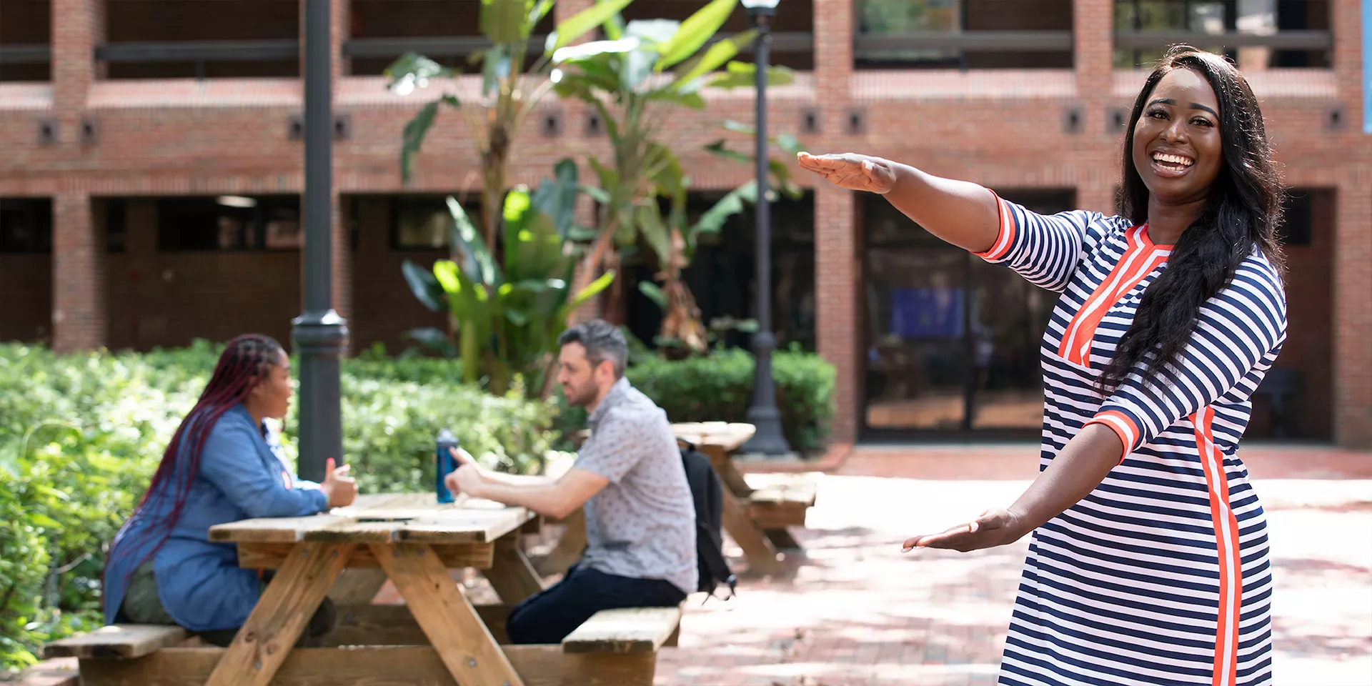 student gator clapping in front of a building